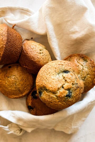 A bunch oat flour blueberry muffins on a white napkin.