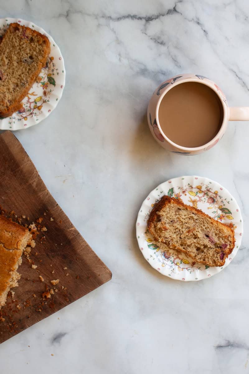 A cup of coffee, two slices of rhubarb bread, and the loaf on a cutting board.