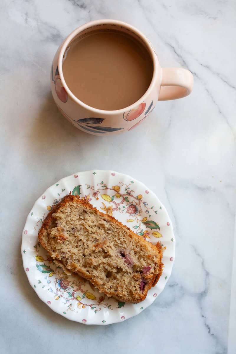 A cup of coffee and a slice of rhubarb bread on a plate.