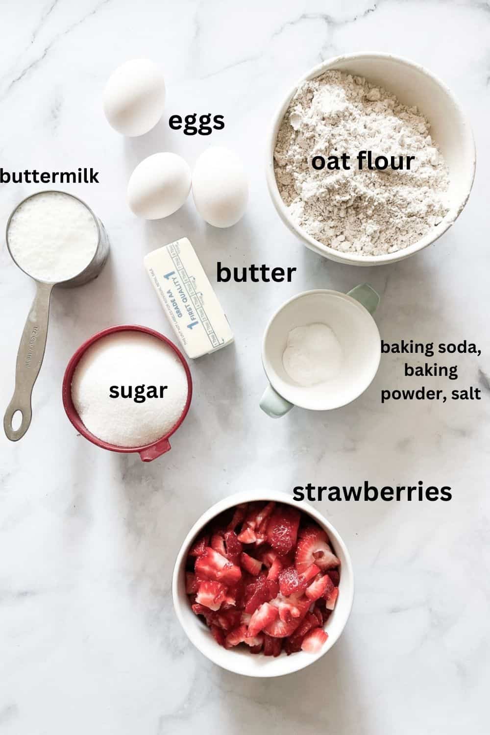 Ingredients for gluten free strawberry buttermilk cake are labeled and portioned: oat flour, baking powder, baking soda, salt, buttermilk, eggs, sugar, strawberries, butter.