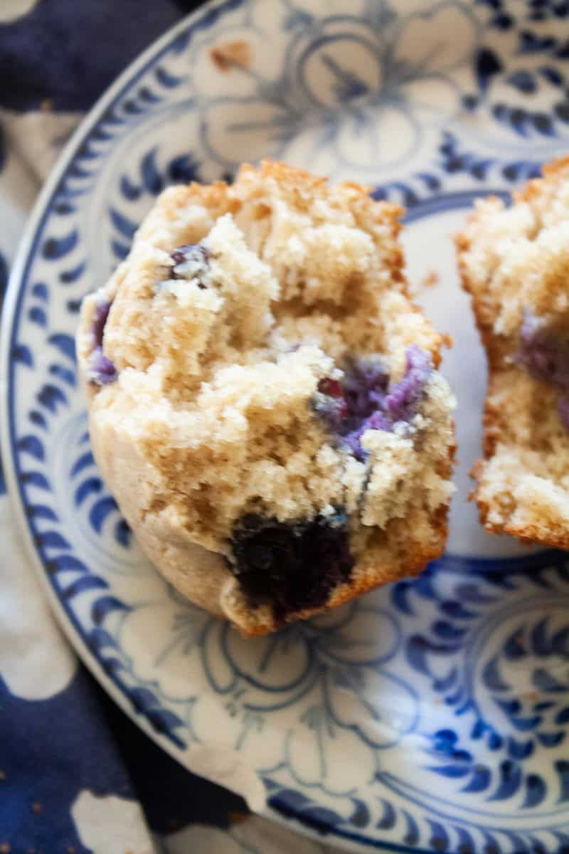 A close up of half of a gluten free banana blueberry muffin on a plate.