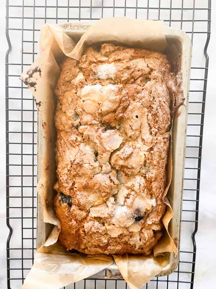 The gluten free blueberry bread cools in a pan on a rack.