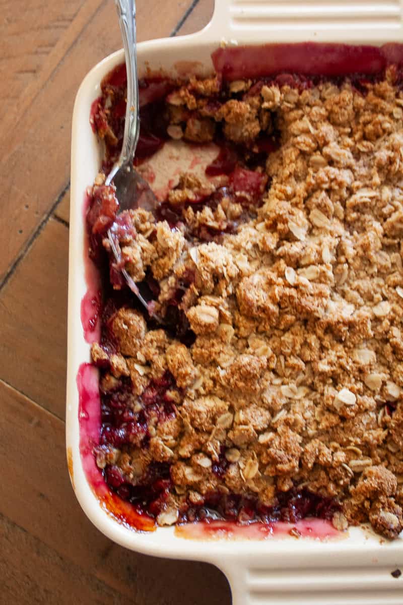 A close up of a pan of gluten free cherry crisp with a spoon in it.