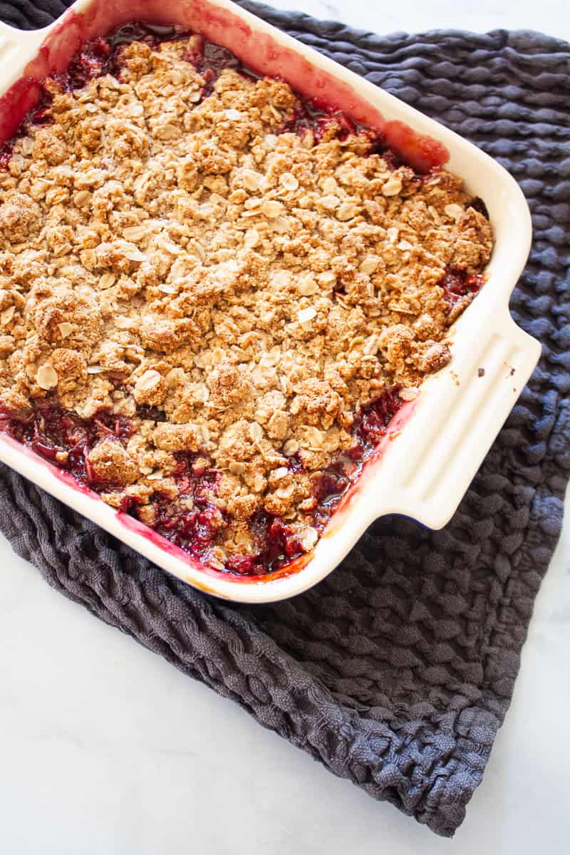 A pan of gluten free cherry crisp on a blue towel.