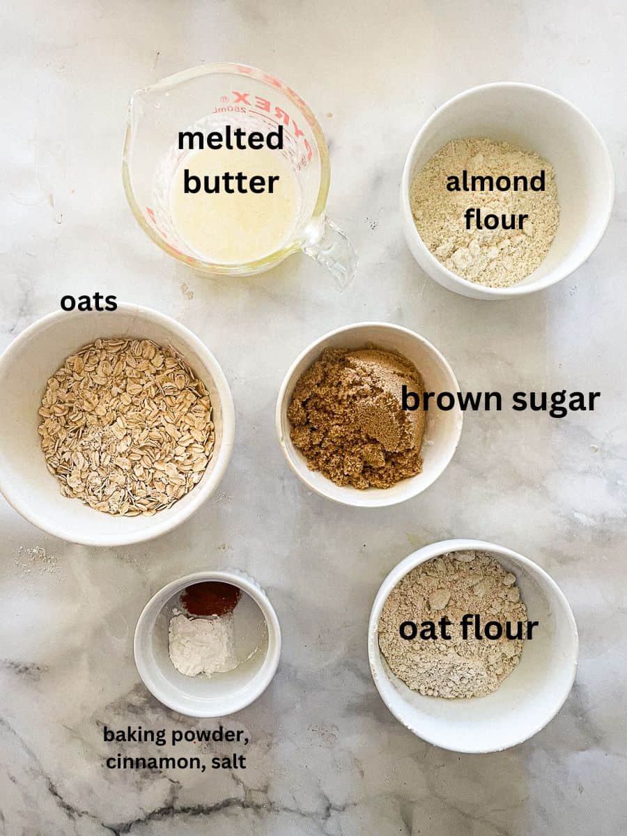 Ingredients for cherry crisp topping are shown labelled and portioned: melted butter, oats, brown sugar, baking powder, cinnamon, and salt, oat flour, almond flour.