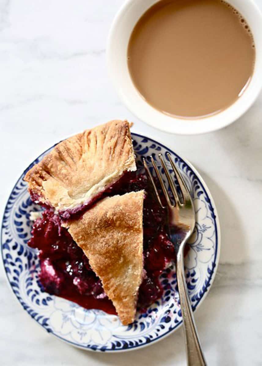 A slice of blueberry blackberry pie is served on a plate with a fork.