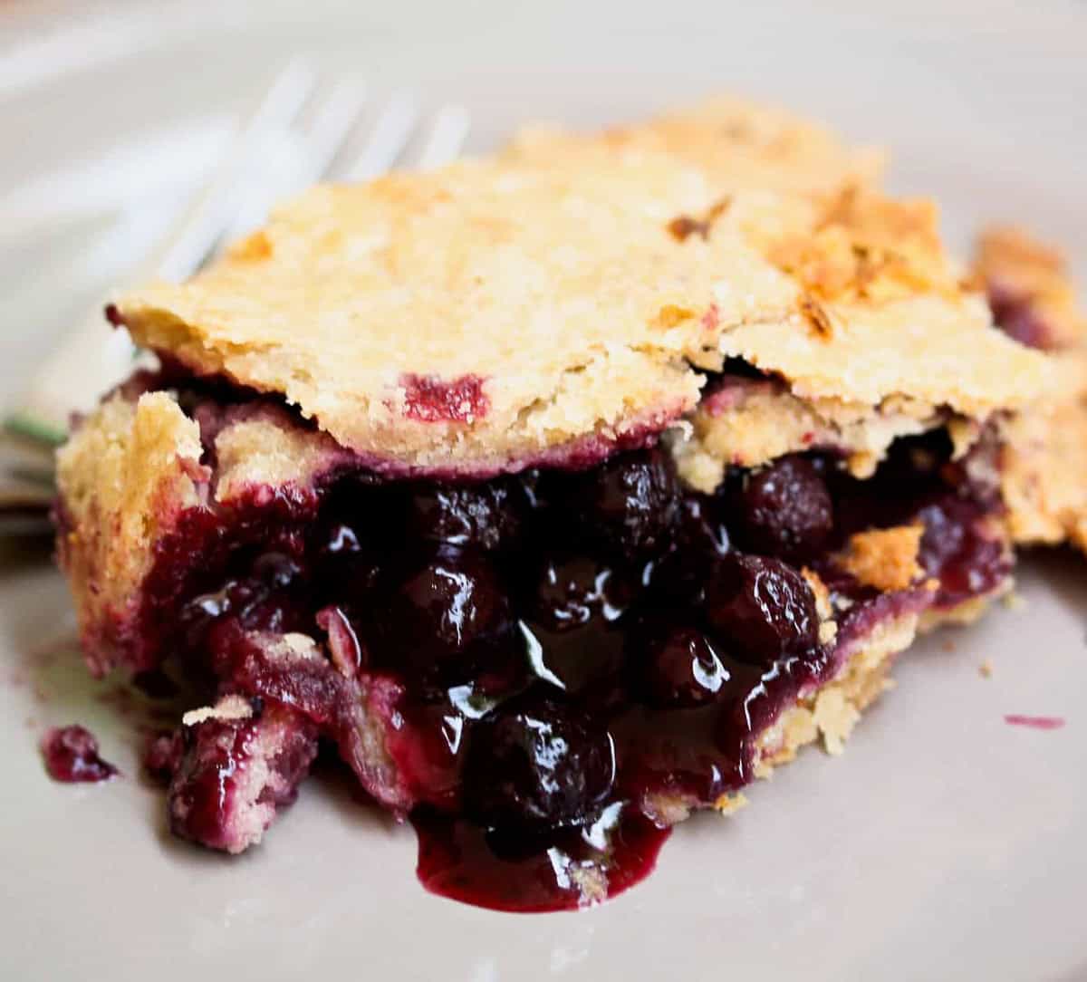 A juicy piece of blueberry blackberry pie on a plate.