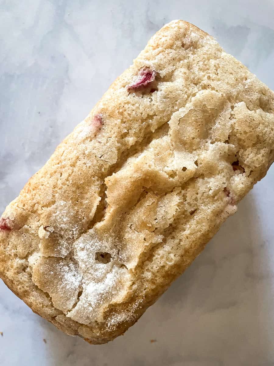 A close up of a loaf of gluten free strawberry rhubarb bread topped with sugar.