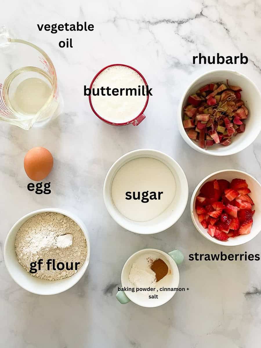 Ingredients for gluten free strawberry rhubarb bread are labeled and portioned: gluten free lfour, baking powder, salt, cinnamon, buttermil, egg, oil, strawberries, rhubarb, sugar.