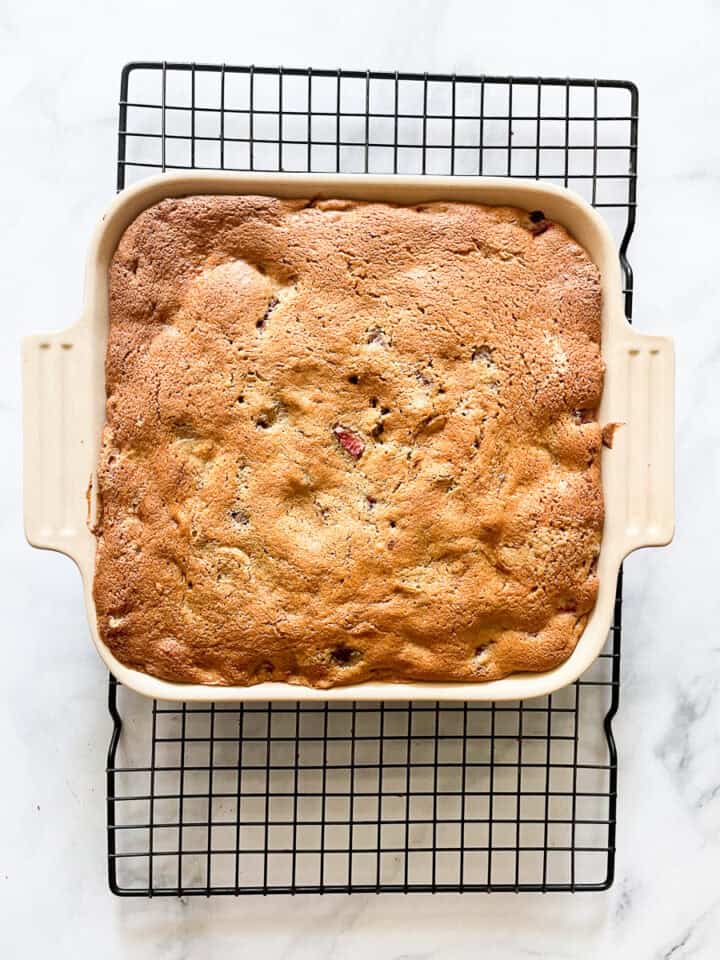 The strawberry cake cools in the pan on a rack.