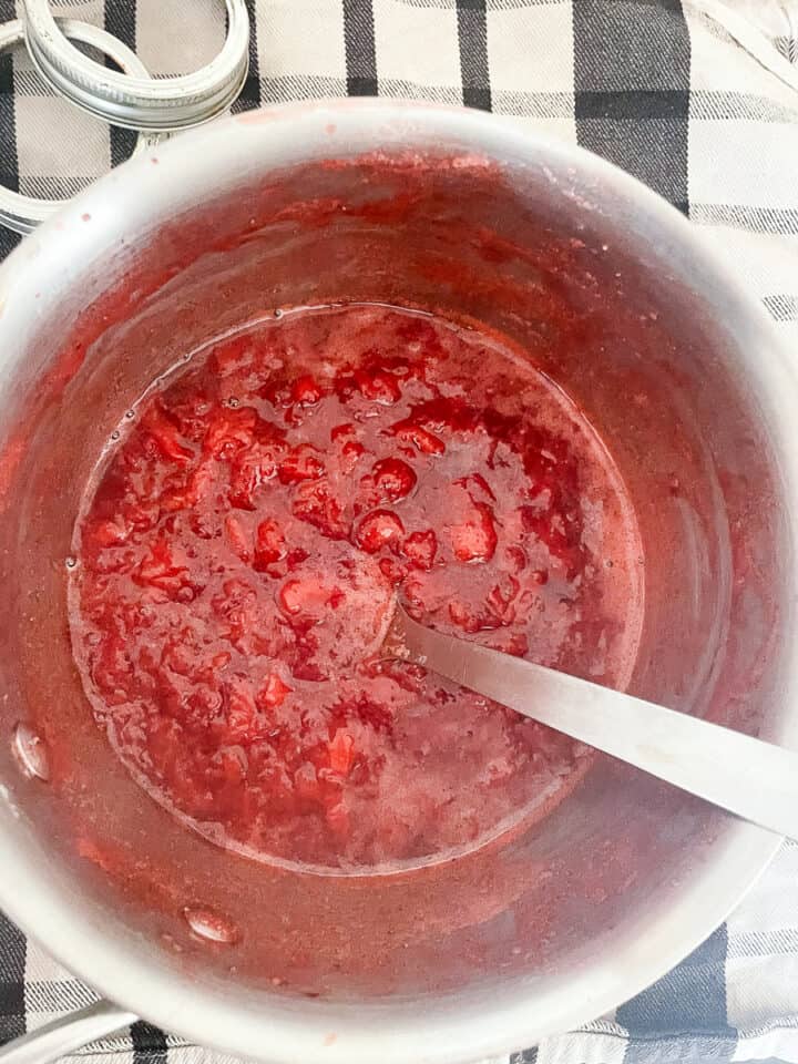 A spoon stirs the strawberry honey jam.