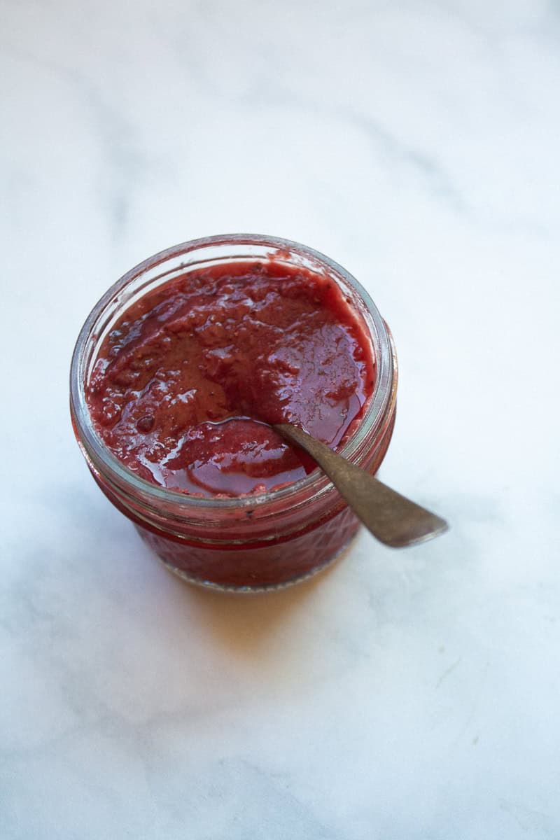 A jar of strawberry honey jam with a spoon.