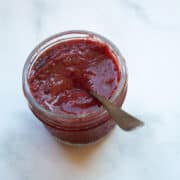A jar of strawberry honey jam with a spoon.