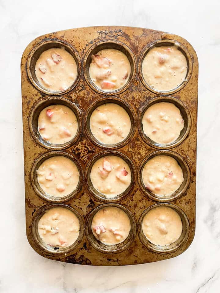 Strawberry banana muffin batter in a 12-cup muffin tin.