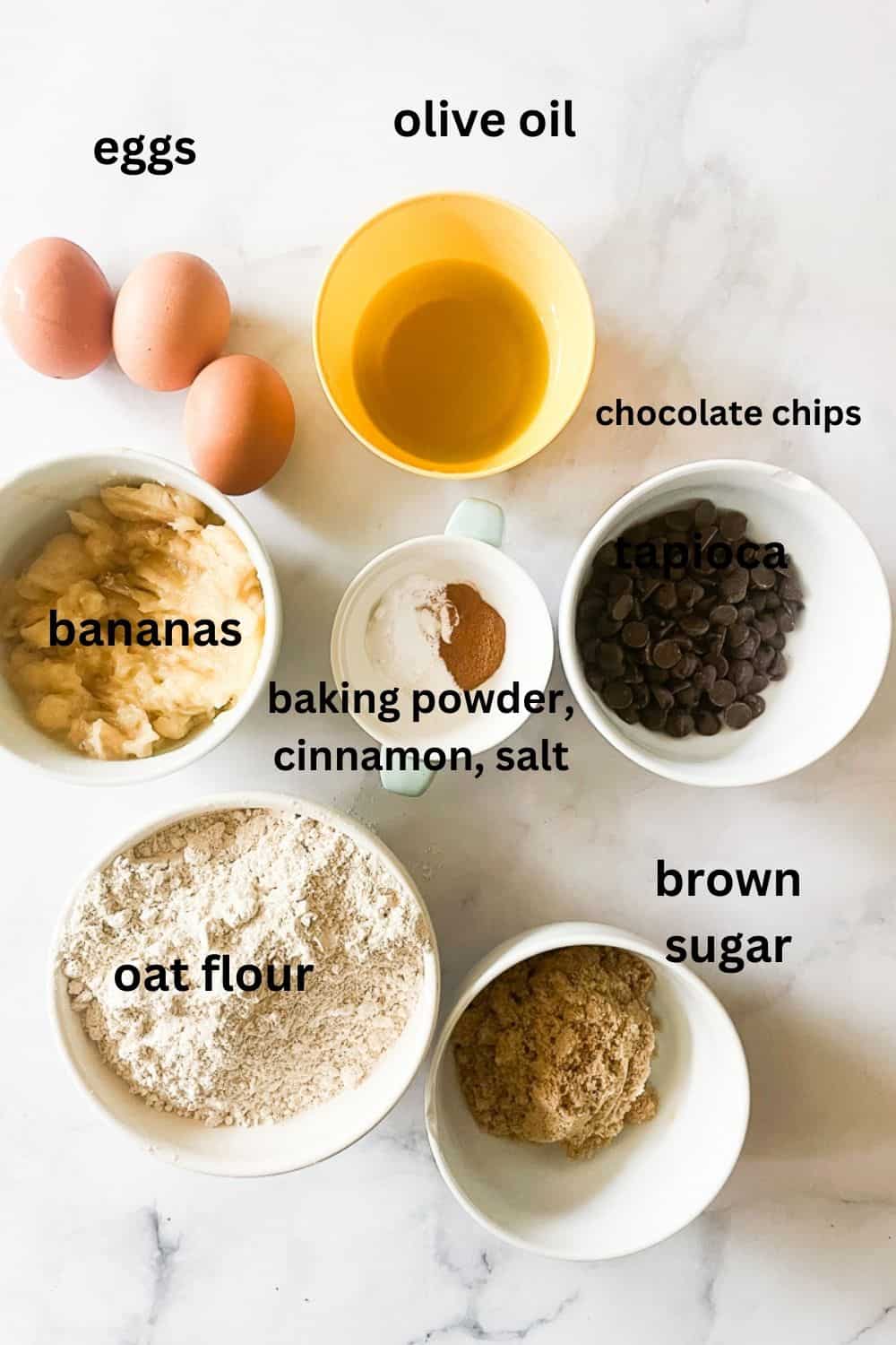 Ingredients for oat flour banana bread - oat flour, eggs, bananas, olive oil baking powder, salt, cinnamon, chocolate chips, brown sugar.