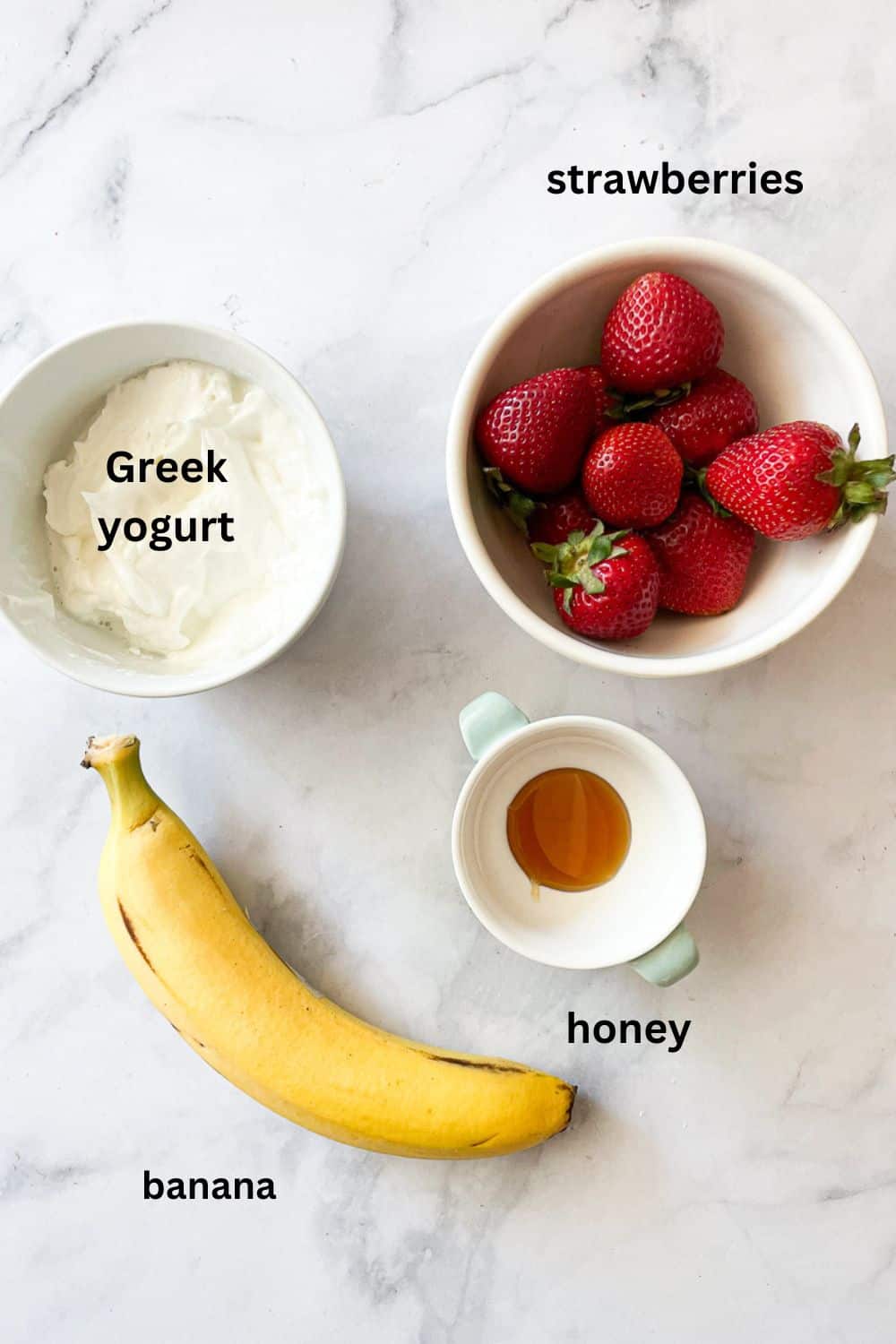 Banana strawberry smoothie ingredients are shown labelled: Greek yogurt, strawberries, honey, banana.