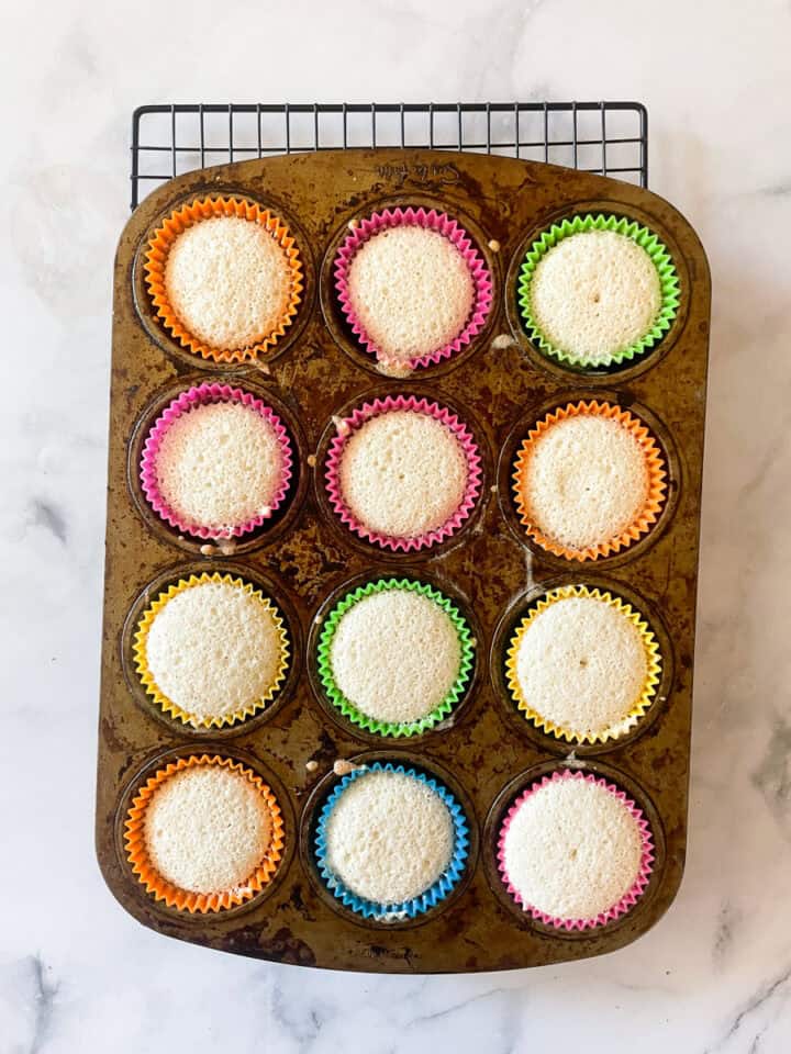 The angel food cupcakes cool in the tin.