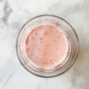 A top down view of a glass of banana strawberry smoothie.