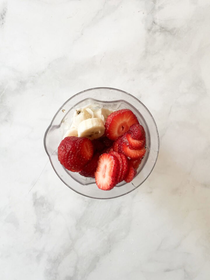 Smoothie ingredients are added to a blender.