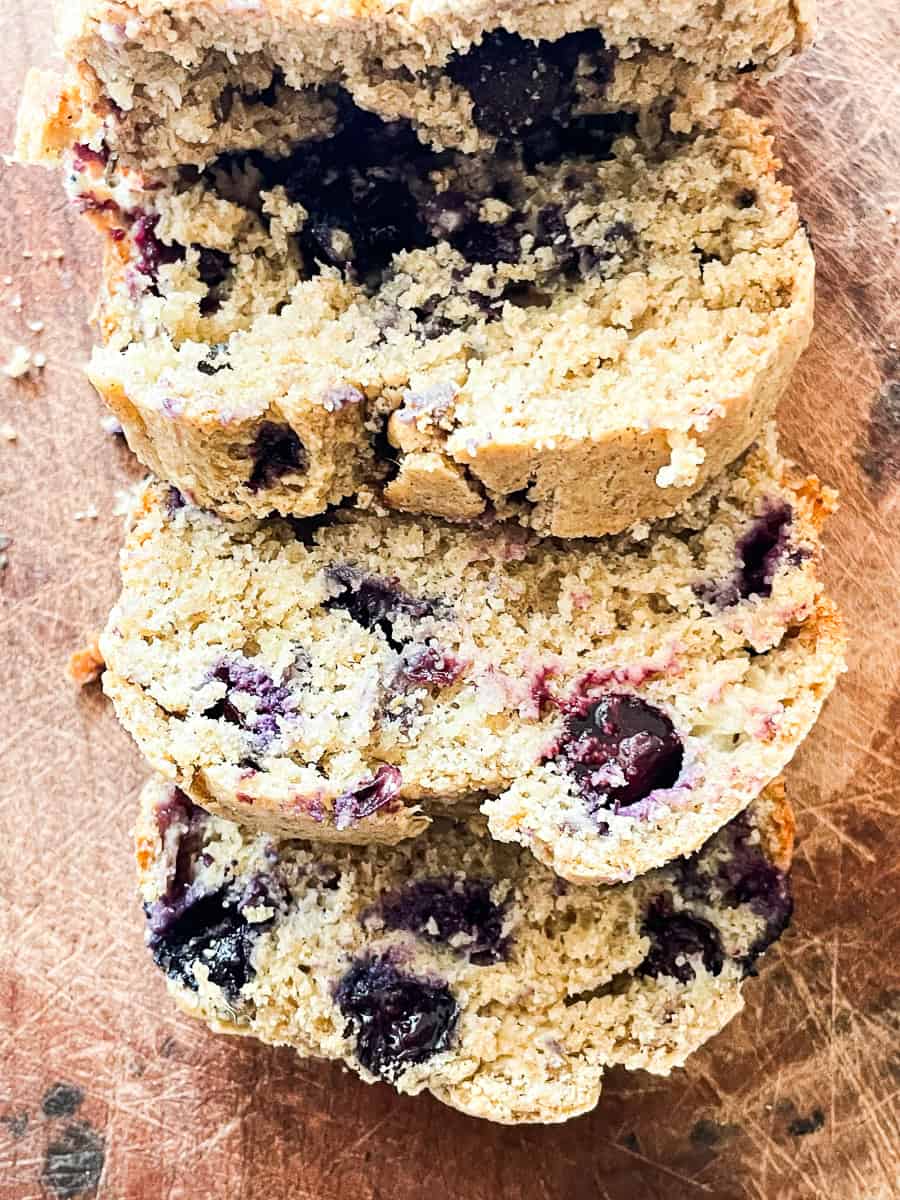 Slices of gluten free blueberry banana bread on a cutting board.