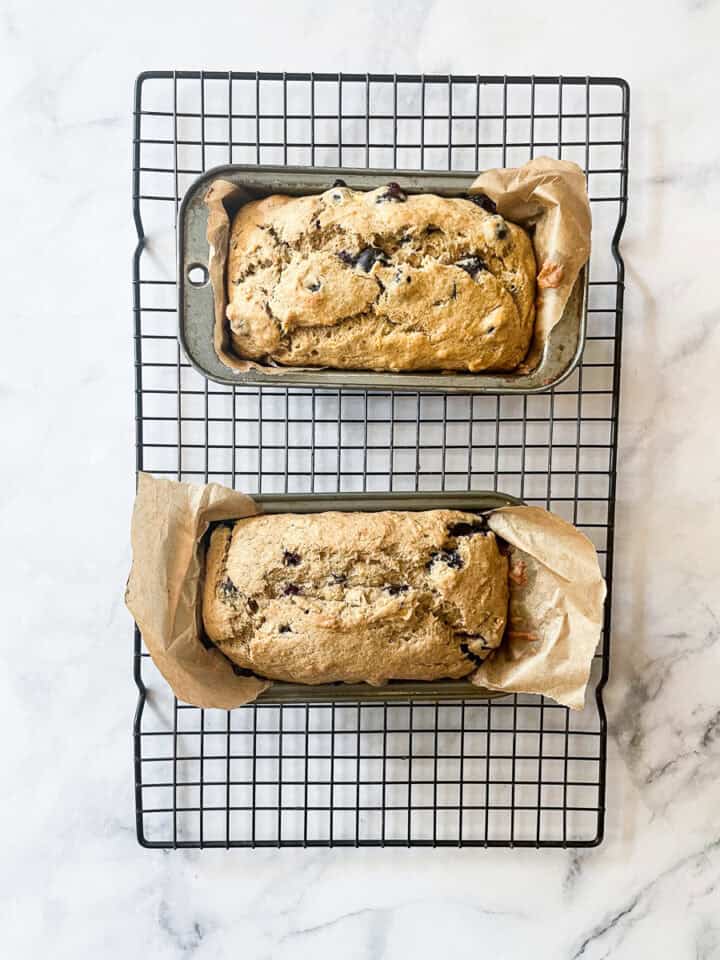 Two mini loaves of gluten free blueberry banana bread cool on a rack.