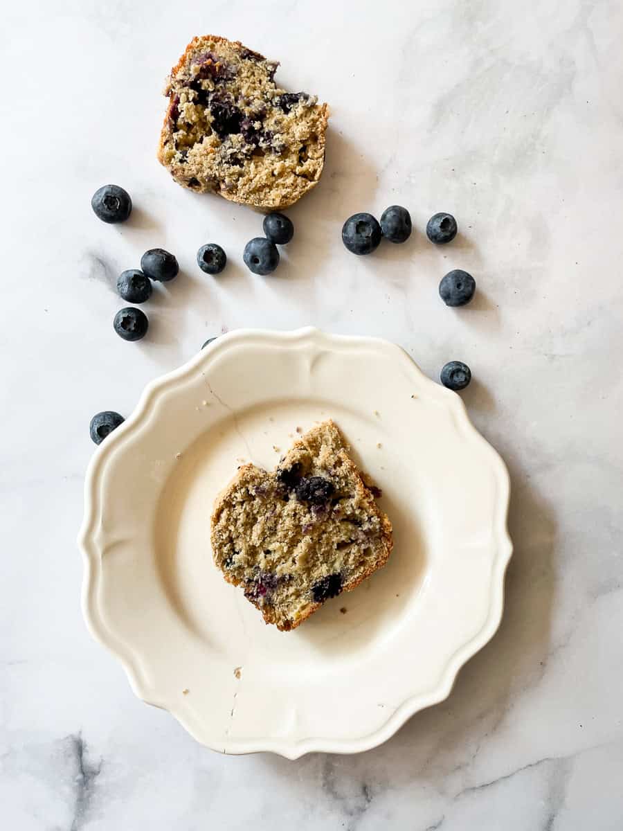 Slices of gluten free blueberry banana bread surrounded by blueberries.