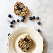 Slices of gluten free blueberry banana bread surrounded by blueberries.