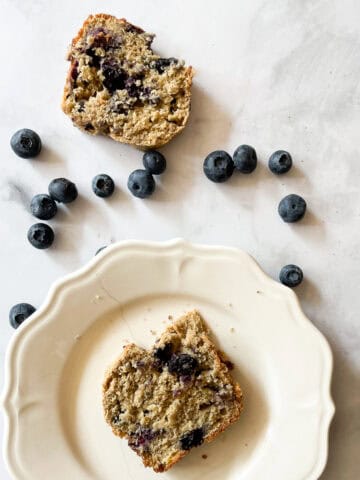 Slices of gluten free blueberry banana bread surrounded by blueberries.