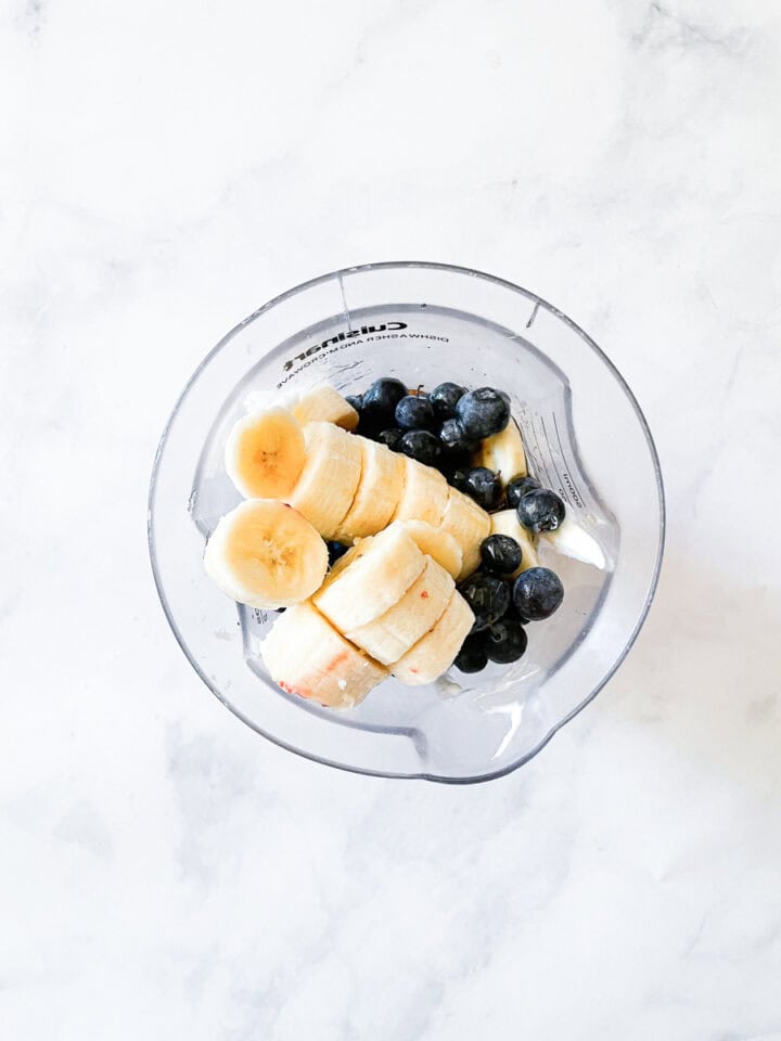 Smoothie ingredients are added to a blender.