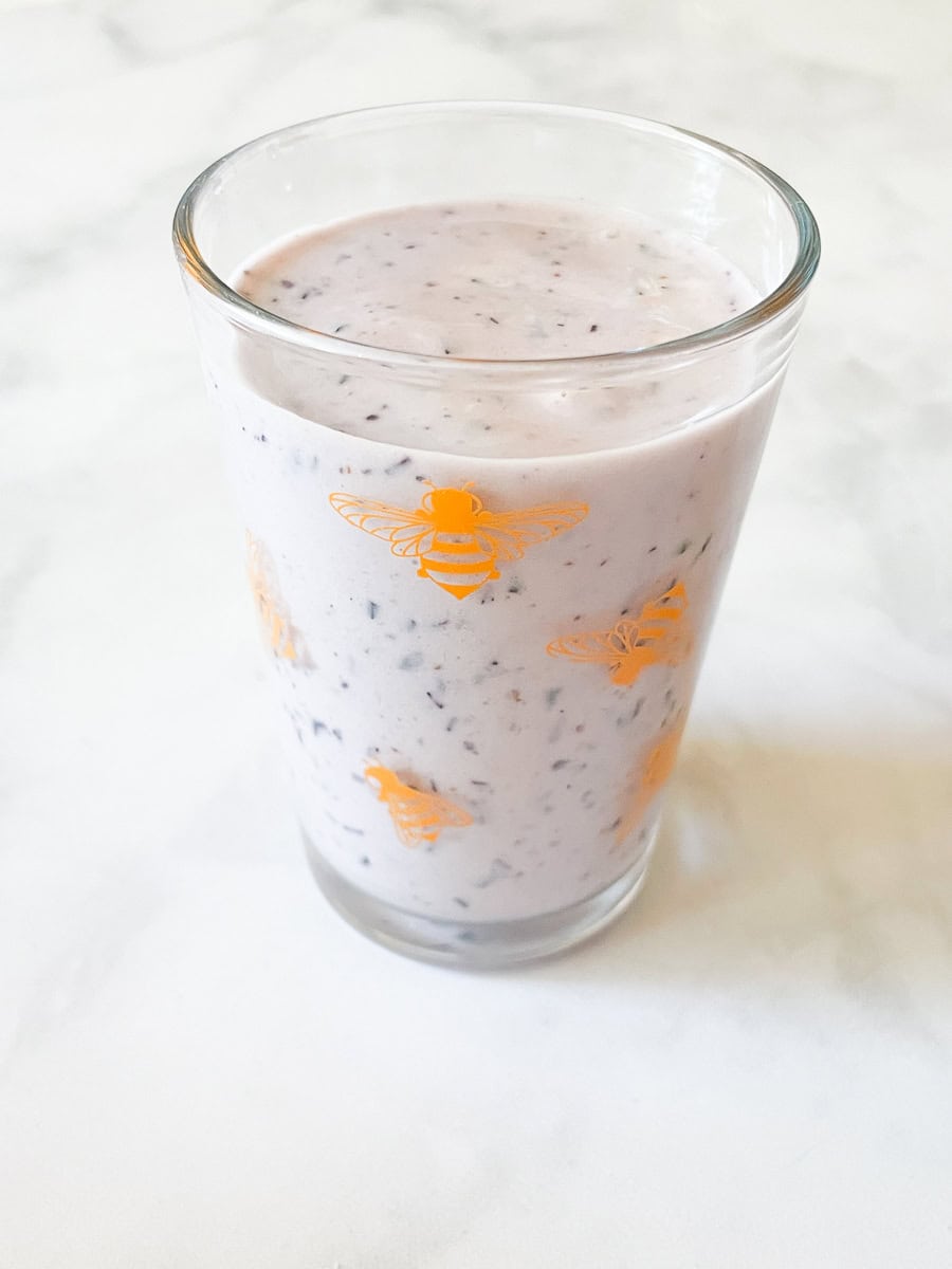 Dragonflies decorate a glass of blueberry banana smoothie.