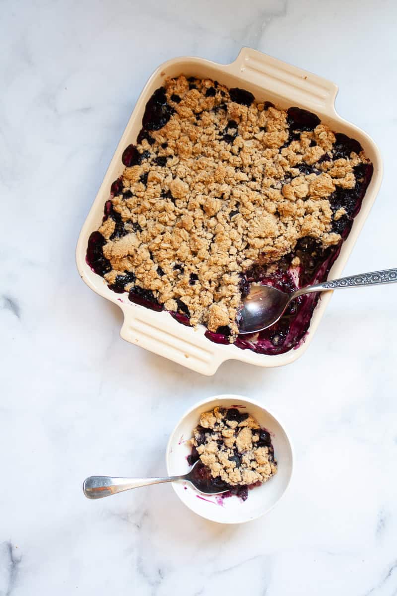 A pan of blueberry crisp and a serving of crisp.