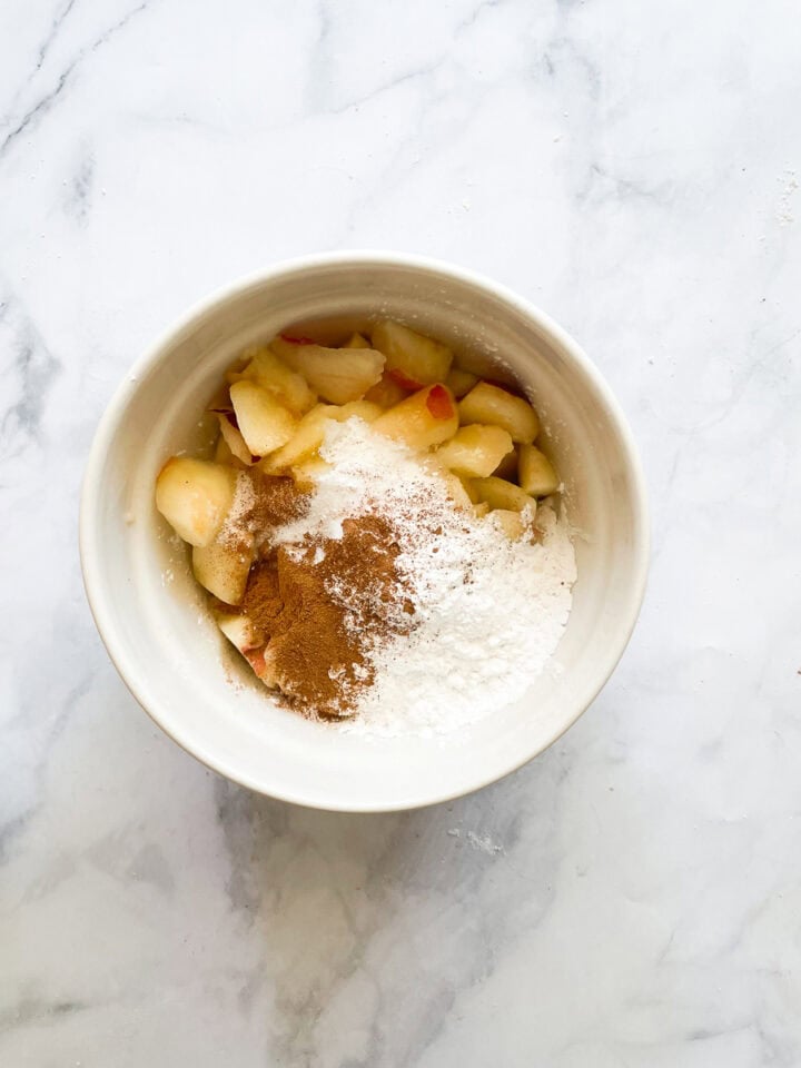 Peach pie filling ingredients added to a bowl.