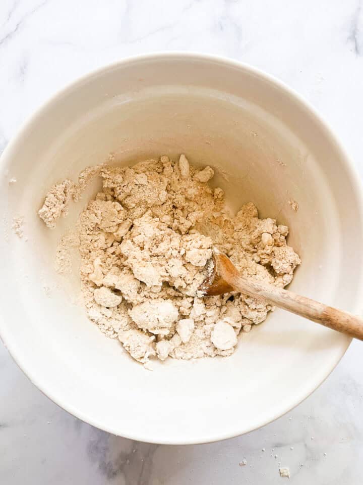 A wooden spoon stirs the pie dough.