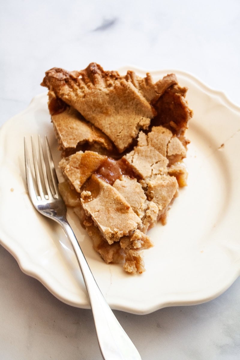 A slice of gluten free peach pie on a plate with a fork.