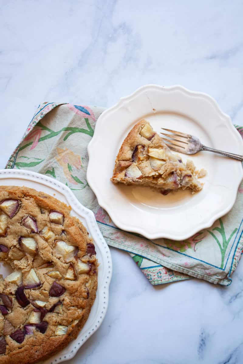 A peach cake with a slice of cake on a plate to its right.