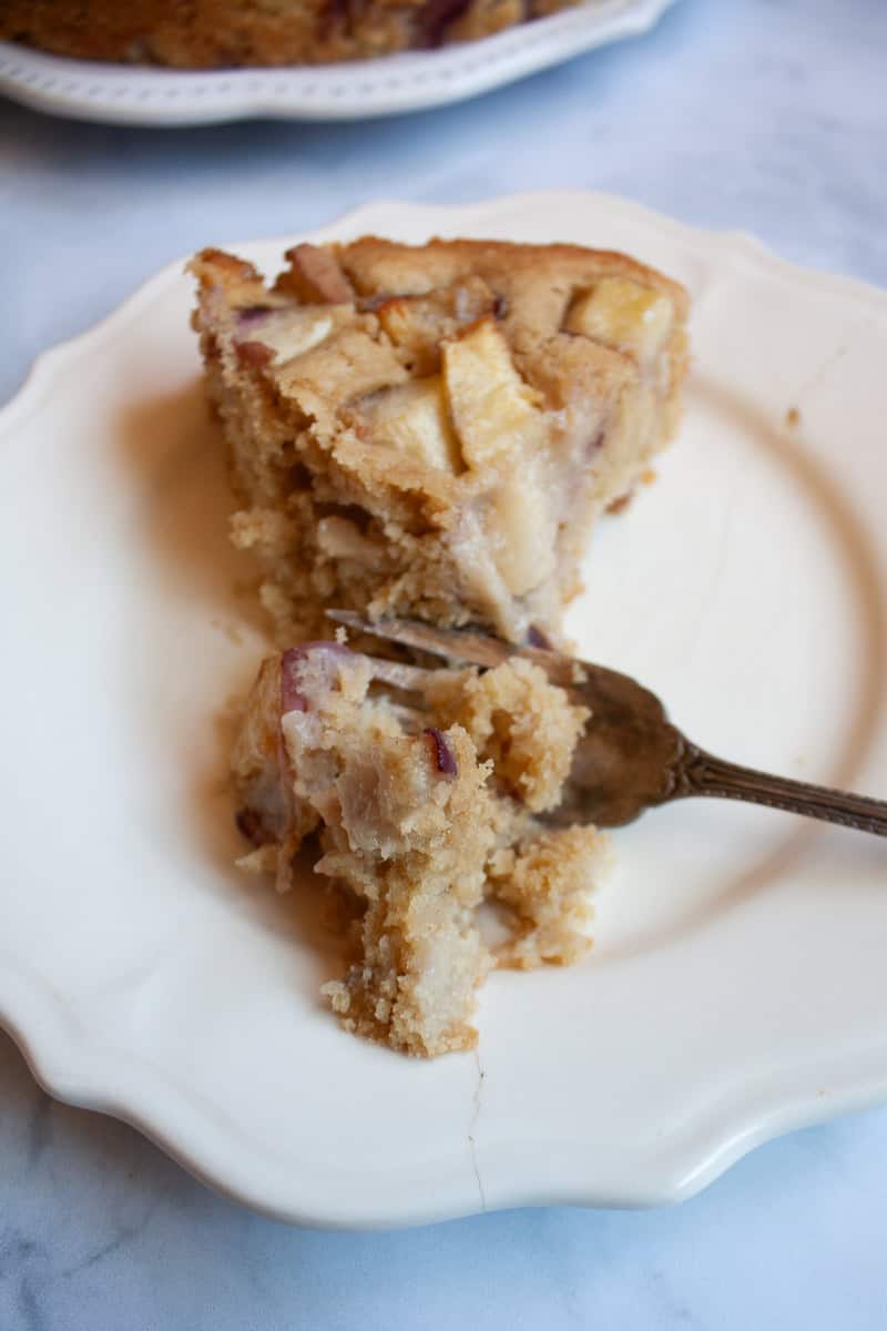 A fork cuts into a slice of gluten free peach cake.