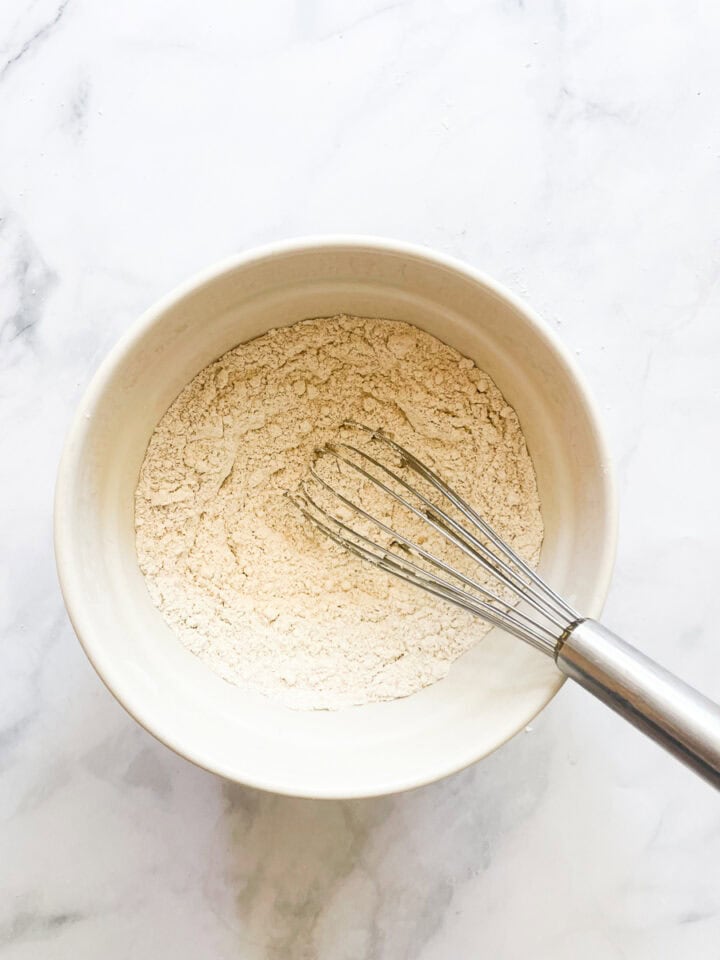 Dry ingredients are whisked for peach cake.