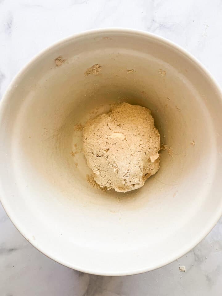 The ball of dough is squeezed together in a bowl.