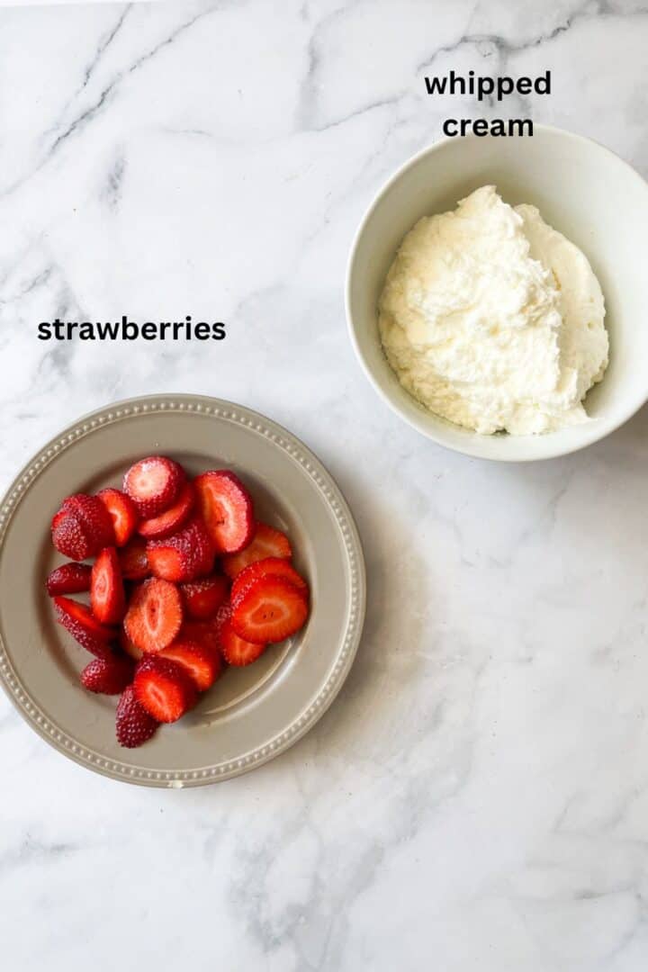 A plate of strawberries and a bowl of whipped cream.