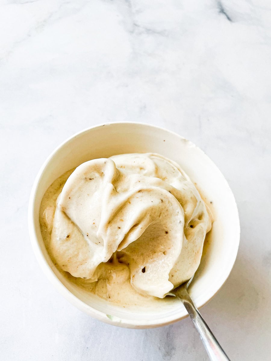 Banana ice cream in a white bowl with a spoon.