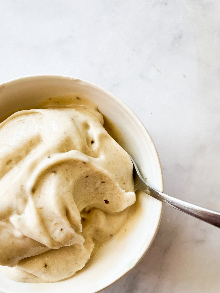 A spoon dips into a creamy bowl of banana ice cream.