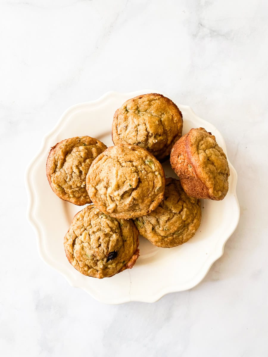 A pile of gluten free banana zucchini muffins on a plate.