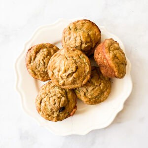 A pile of gluten free banana zucchini muffins on a plate.