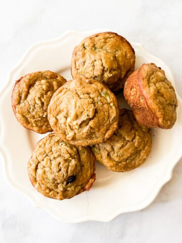 A pile of gluten free banana zucchini muffins on a plate.