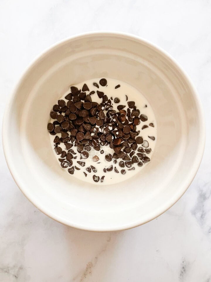 Cream and chocolate chips are combined in a bowl.