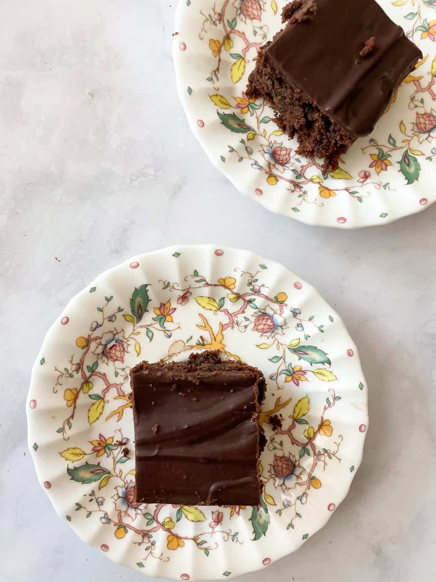 Two flowered plates hold pieces of zucchini chocolate cake.