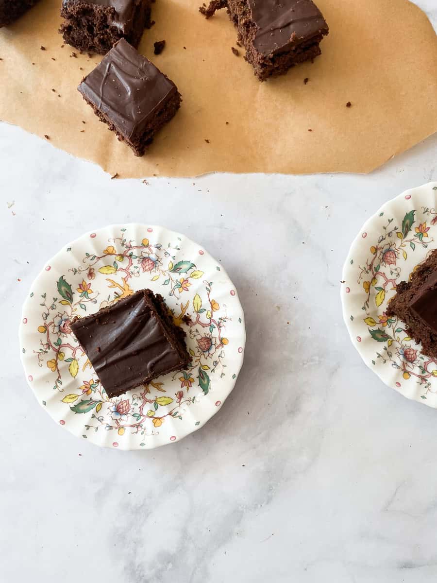 A plate of zucchini chocolate cake next to pieces of cake.