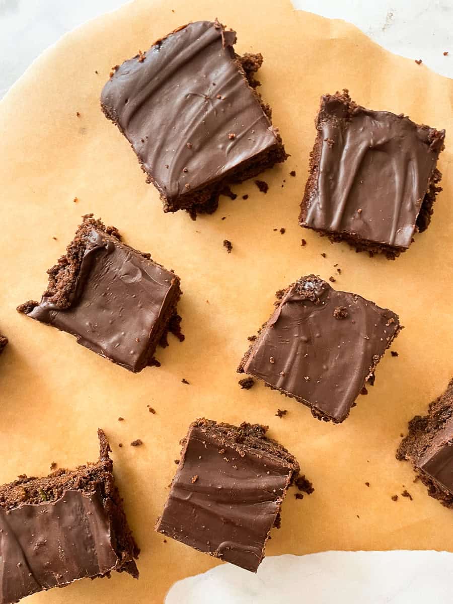 Pieces of zucchini chocolate cake on a piece of parchment.