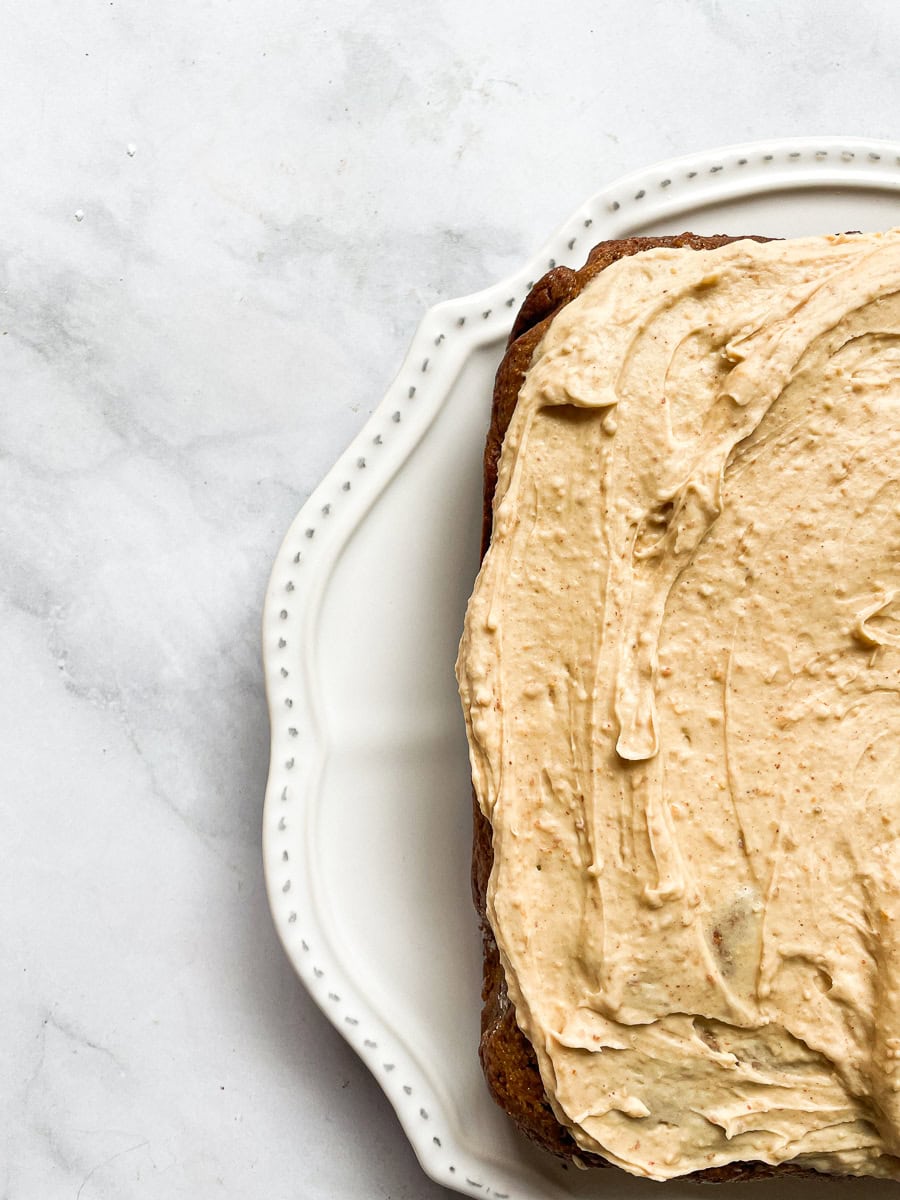 Half of a whole banana peanut butter cake on a white plate.