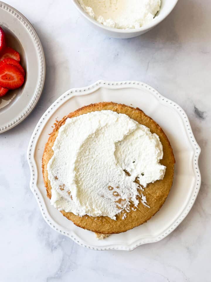 Whipped cream is added to the cake.